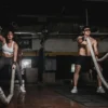 Photo by Leon Ardho Two people engage in a powerful indoor battle rope workout, showcasing strength and energy.