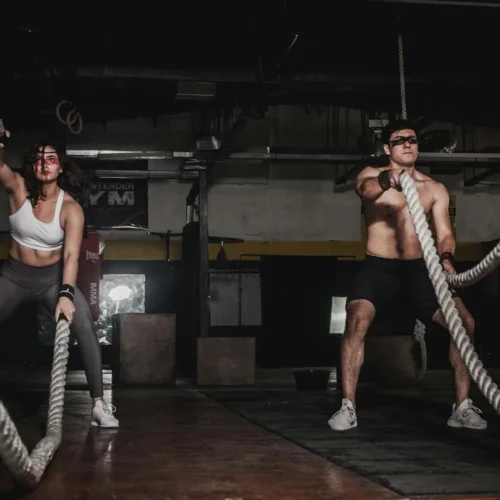Photo by Leon Ardho Two people engage in a powerful indoor battle rope workout, showcasing strength and energy.