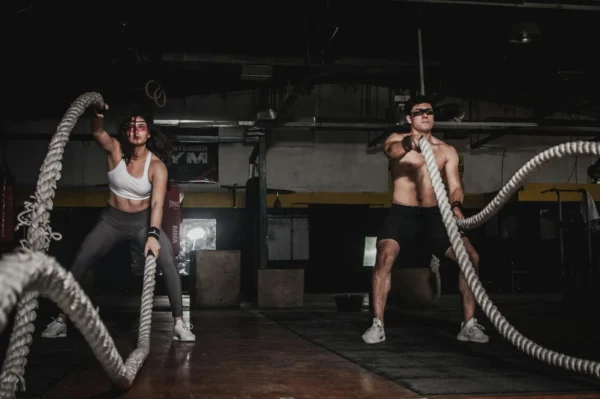 Photo by Leon Ardho Two people engage in a powerful indoor battle rope workout, showcasing strength and energy.