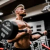 Photo by Anastase Maragos topless man in black shorts carrying black dumbbell