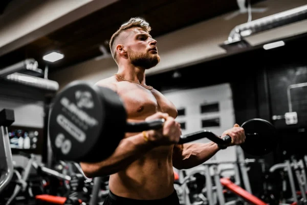 Photo by Anastase Maragos topless man in black shorts carrying black dumbbell