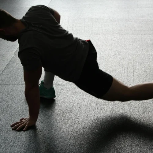 Photo by Pixabay Silhouette of a man executing a stretching routine in a dim gym environment.