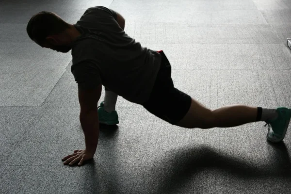 Photo by Pixabay Silhouette of a man executing a stretching routine in a dim gym environment.