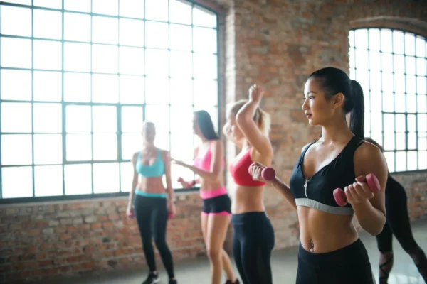 Photo by Andrea Piacquadio Determined pensive Asian female in black activewear holding dumbbells while training in group of other female athletes in in loft spacious gym