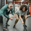 A dedicated woman focuses on battle rope training, guided by her fitness coach.