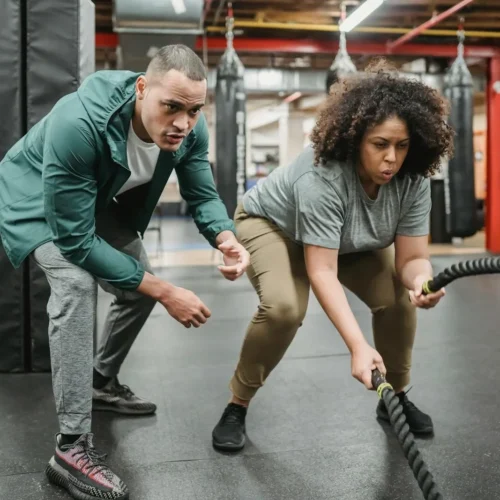 Photo by Julia Larson A dedicated woman focuses on battle rope training, guided by her fitness coach.