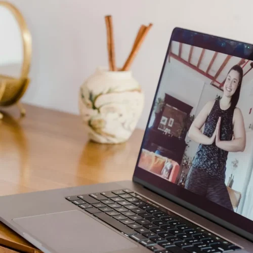Photo by Tim Samuel A woman participates in an online yoga class, seen on a laptop screen at home.